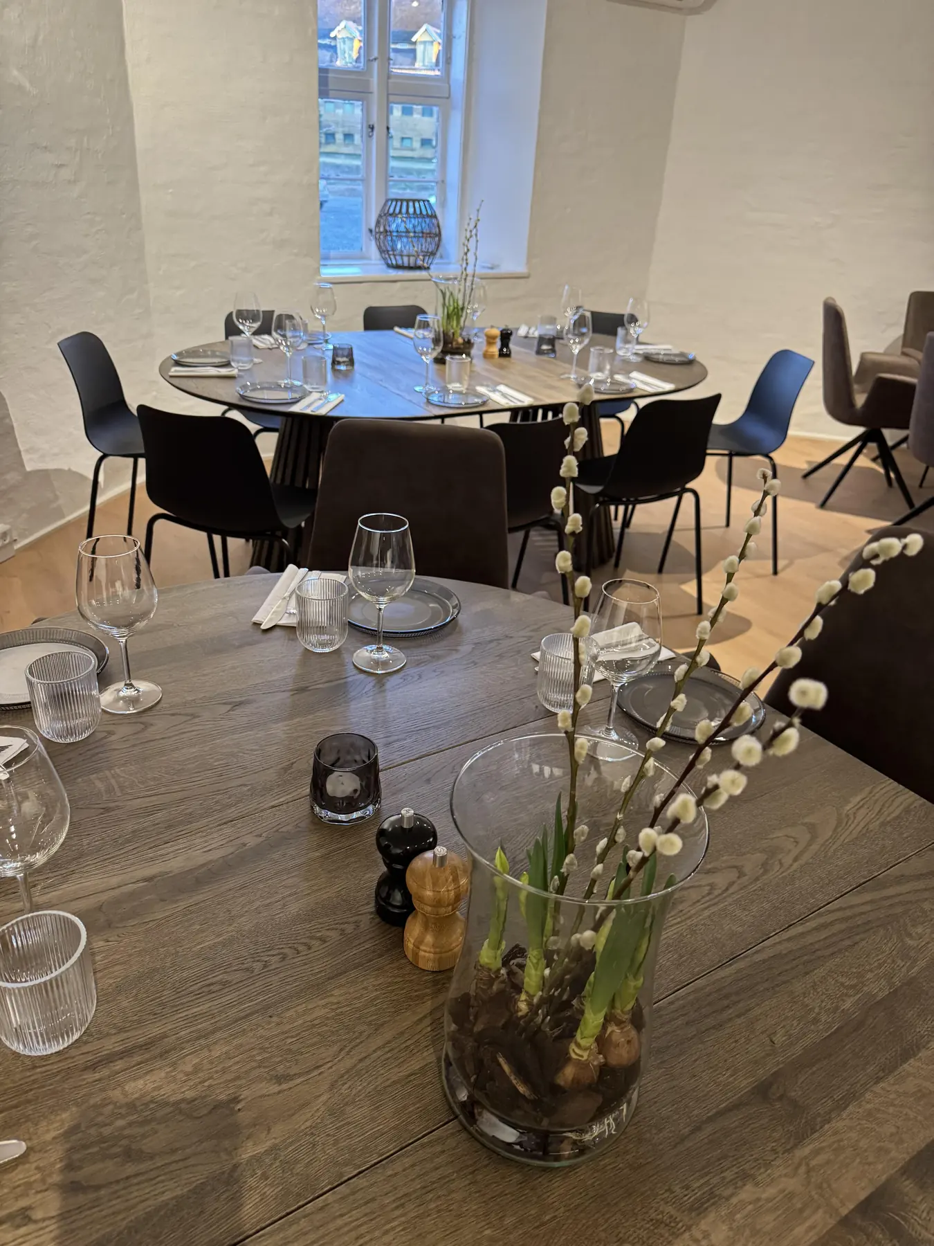 Dækket runde borde i Skænkestuen med glas og grene i vase