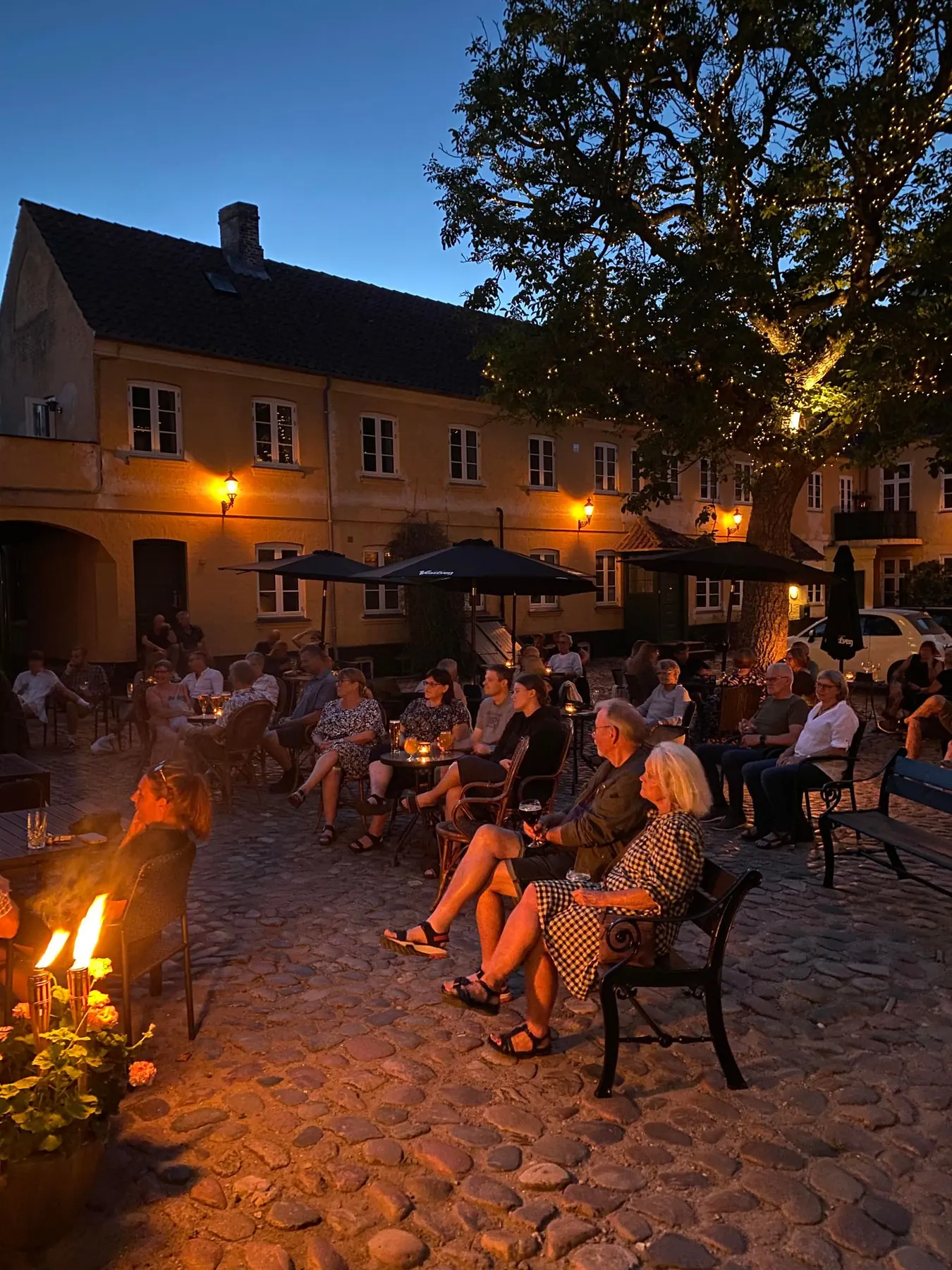Gæster om bålet i gården en sommeraften